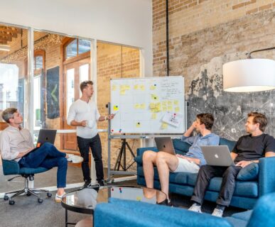 three men sitting while using laptops and watching man beside whiteboard Lead Generation Strategies